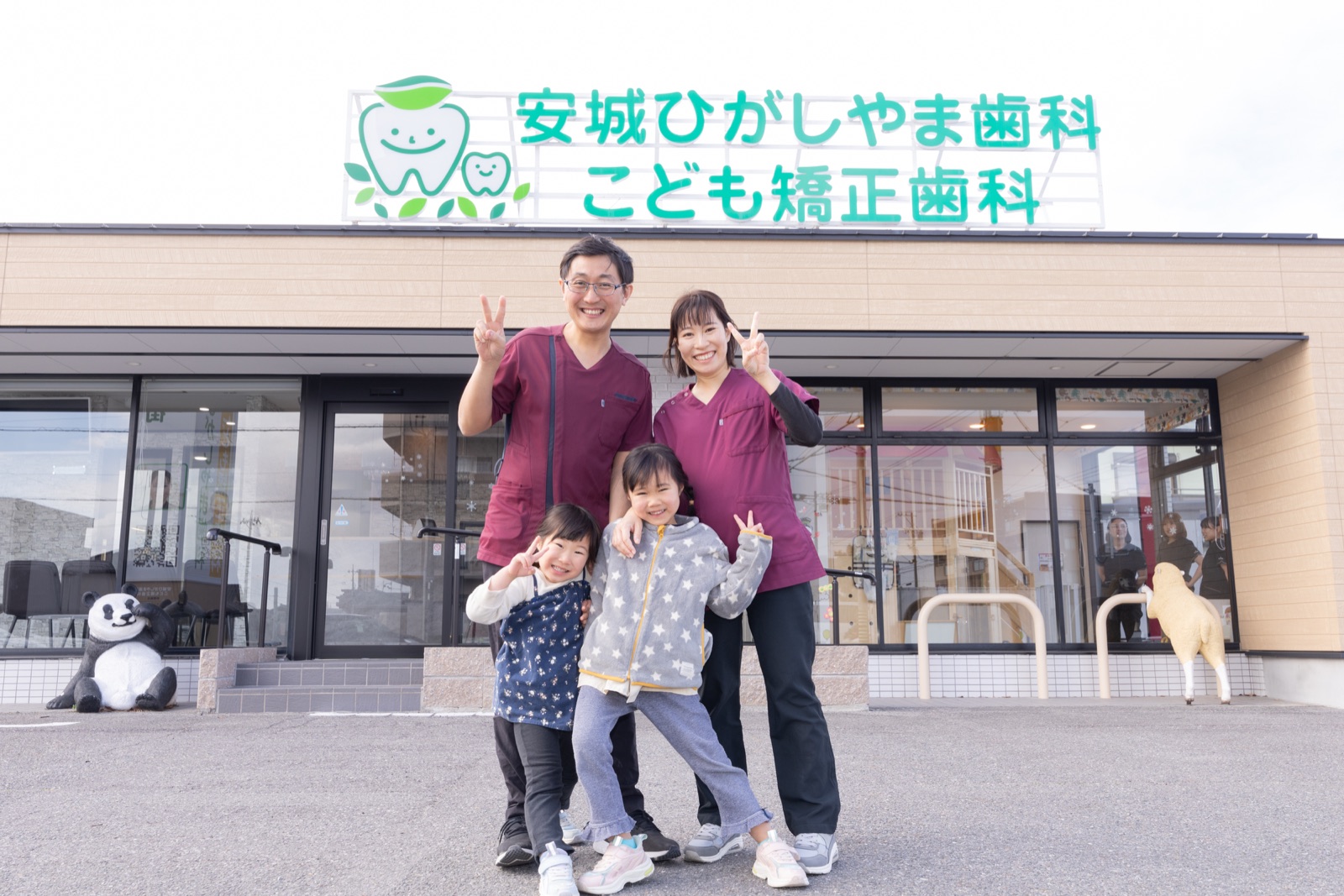 医院の前に立つ歯科医師と家族